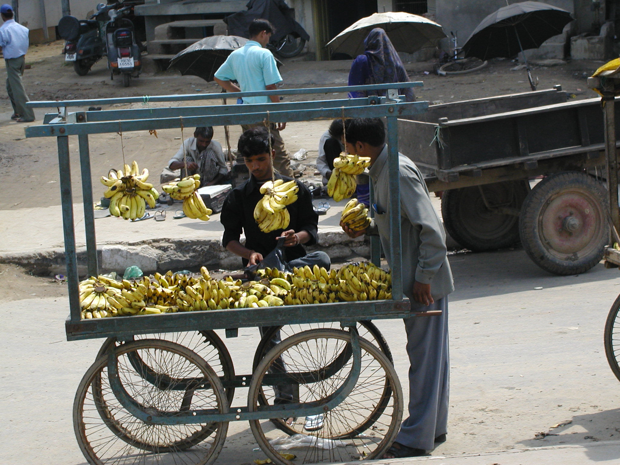 A man selling bananas on the street from his cart 
