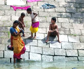 A women does laundry down by the water.