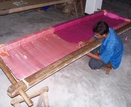 A local Bangladesh man making silk on a loom.