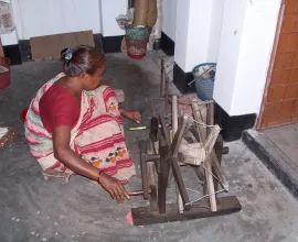 A woman works with a silk loom.