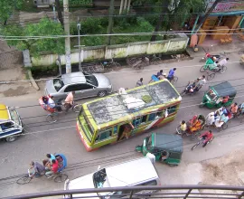 Bike carts, cars, and buses share the road.