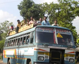 A bus is so crowded that passengers even ride on the top.