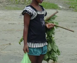 A girl in modern dress carries various items.