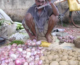 A vendor sells his vegetables at a market in Dumka.