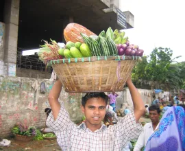 A man carried a basket of vegetables on his head.