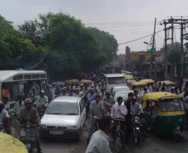 Heavy traffic in India includes vans, cars, bikes, animals, and pedestrians.